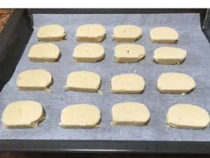 Sliced cookie dough arranged on a lined baking tray